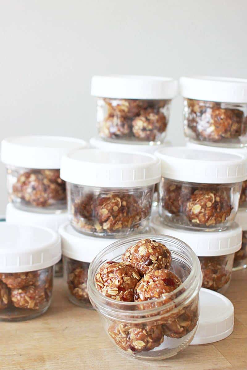 mason jars with white lids full of granola balls with chocolate chips and craisins