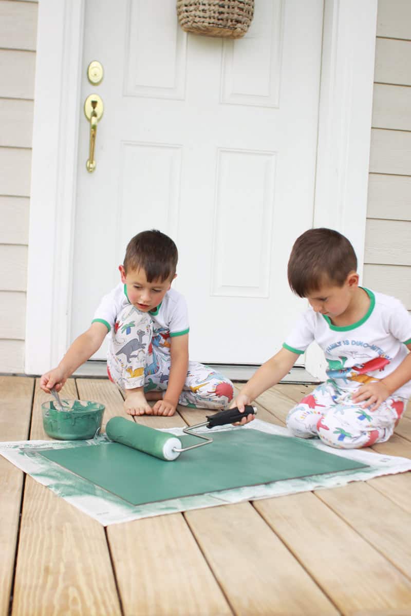 twin boys rolling green paint onto a DIY chalkboard