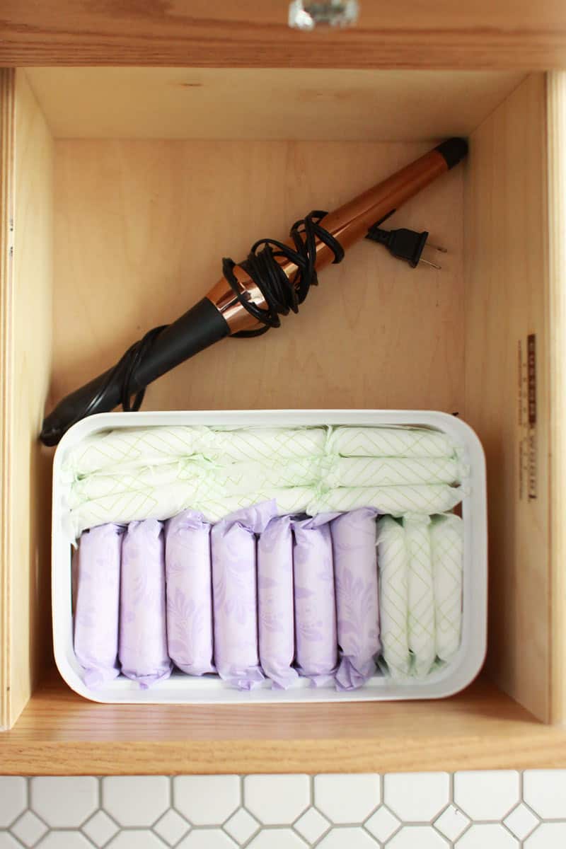 a bathroom drawer with a a bin full of period pads 