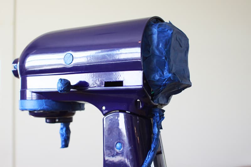 a royal blue KitchenAid mixer with parts taped off with blue painter's tape