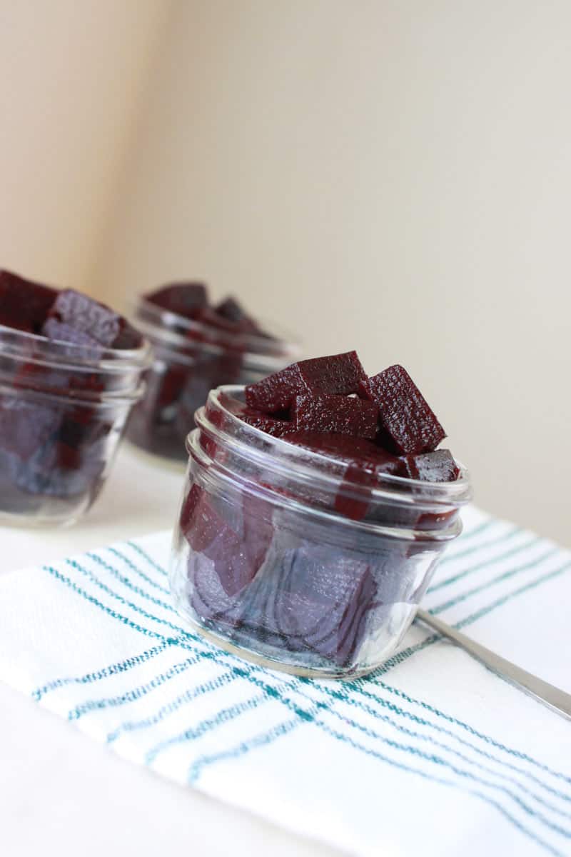 mason jars of homemade berry jello laid out on a white cutting board