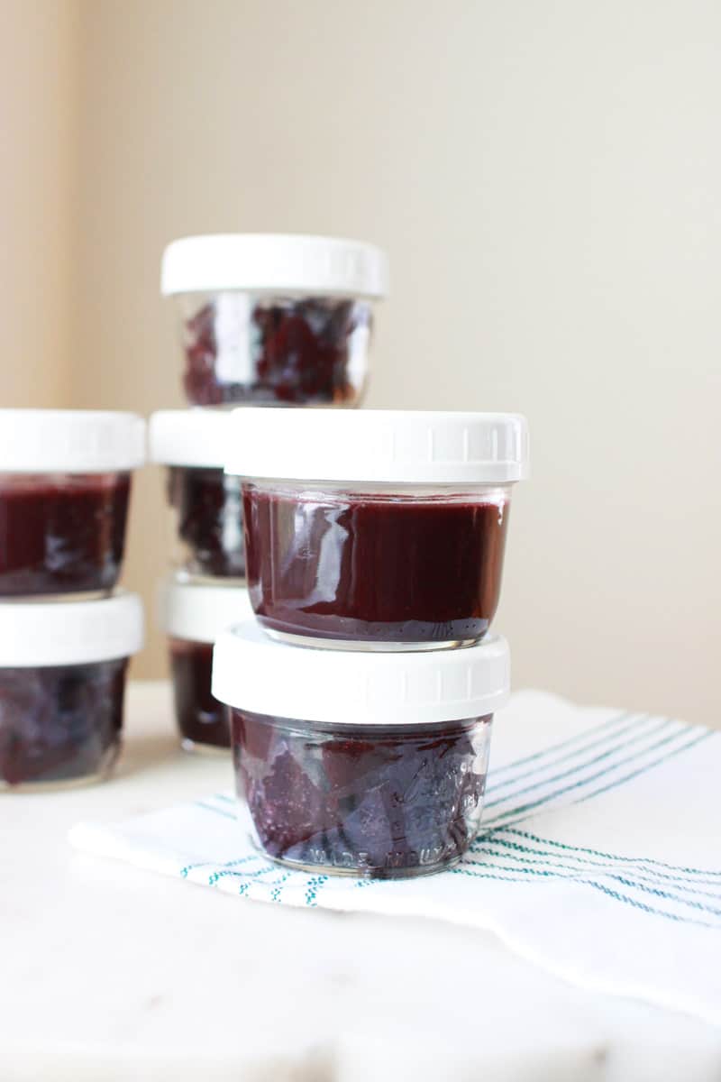 mason jars with lids of homemade berry jello laid out on a white cutting board