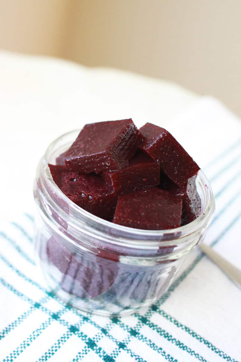 a mason jar of homemade berry jello  on a white cutting board