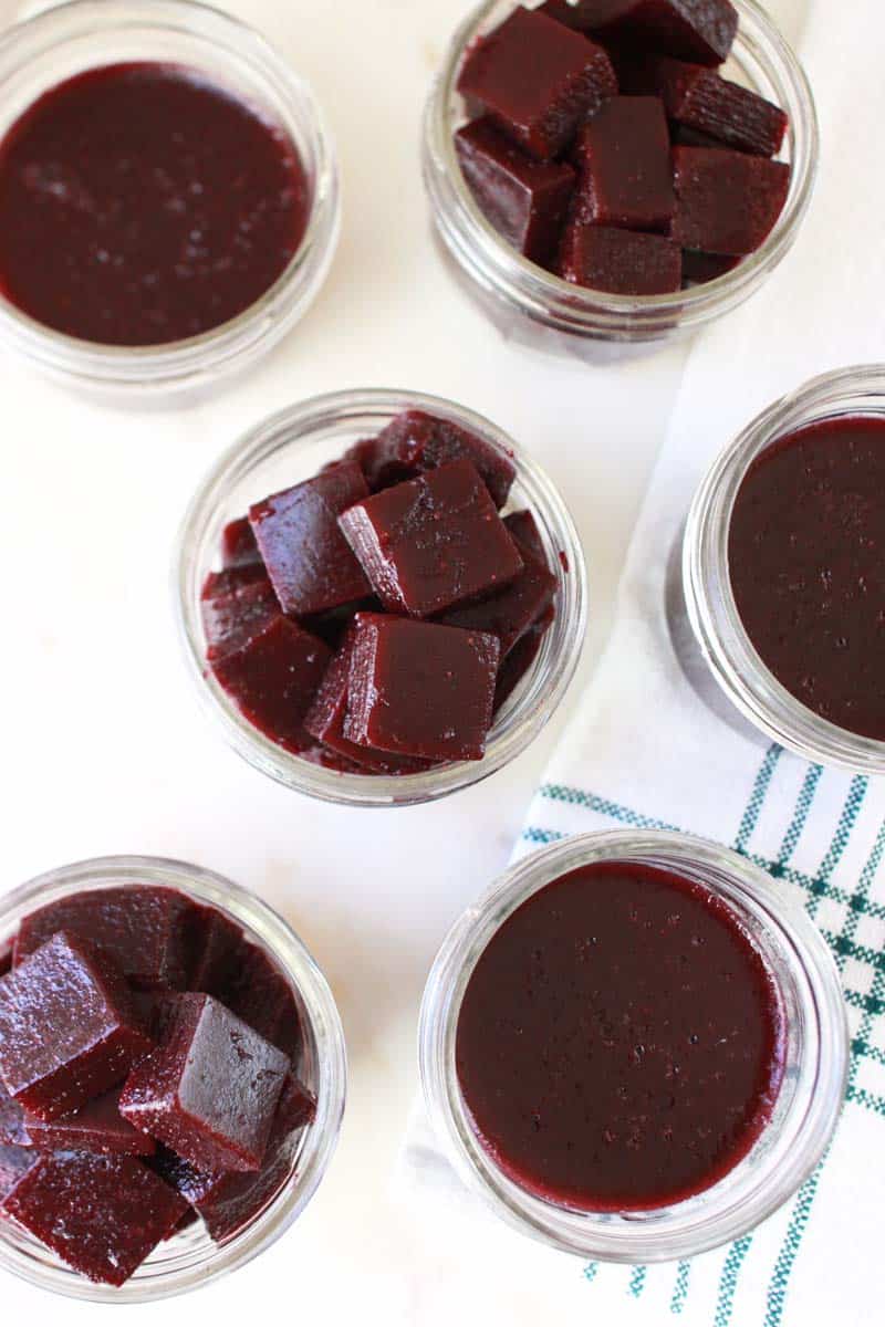 mason jars of homemade berry jello laid out on a white cutting board