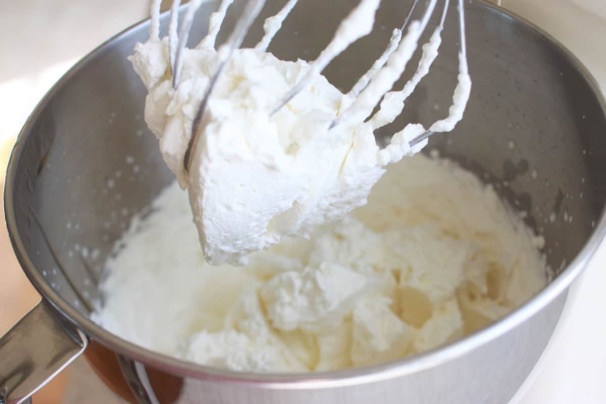 the bowl of a kitchen aid mixer full of whipped cream