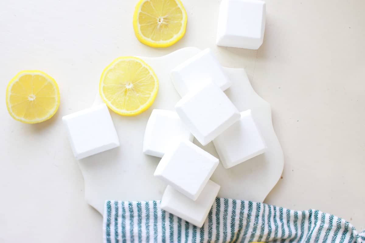 a marble cutting board with toilet cleaner tablets and sliced lemons