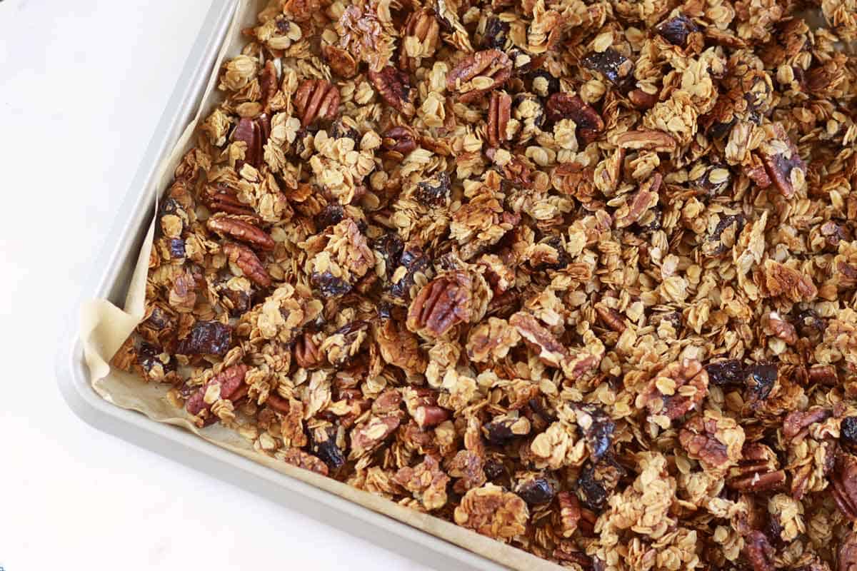 a sheet pan lined with parchment paper homemade granola with pecans and dates