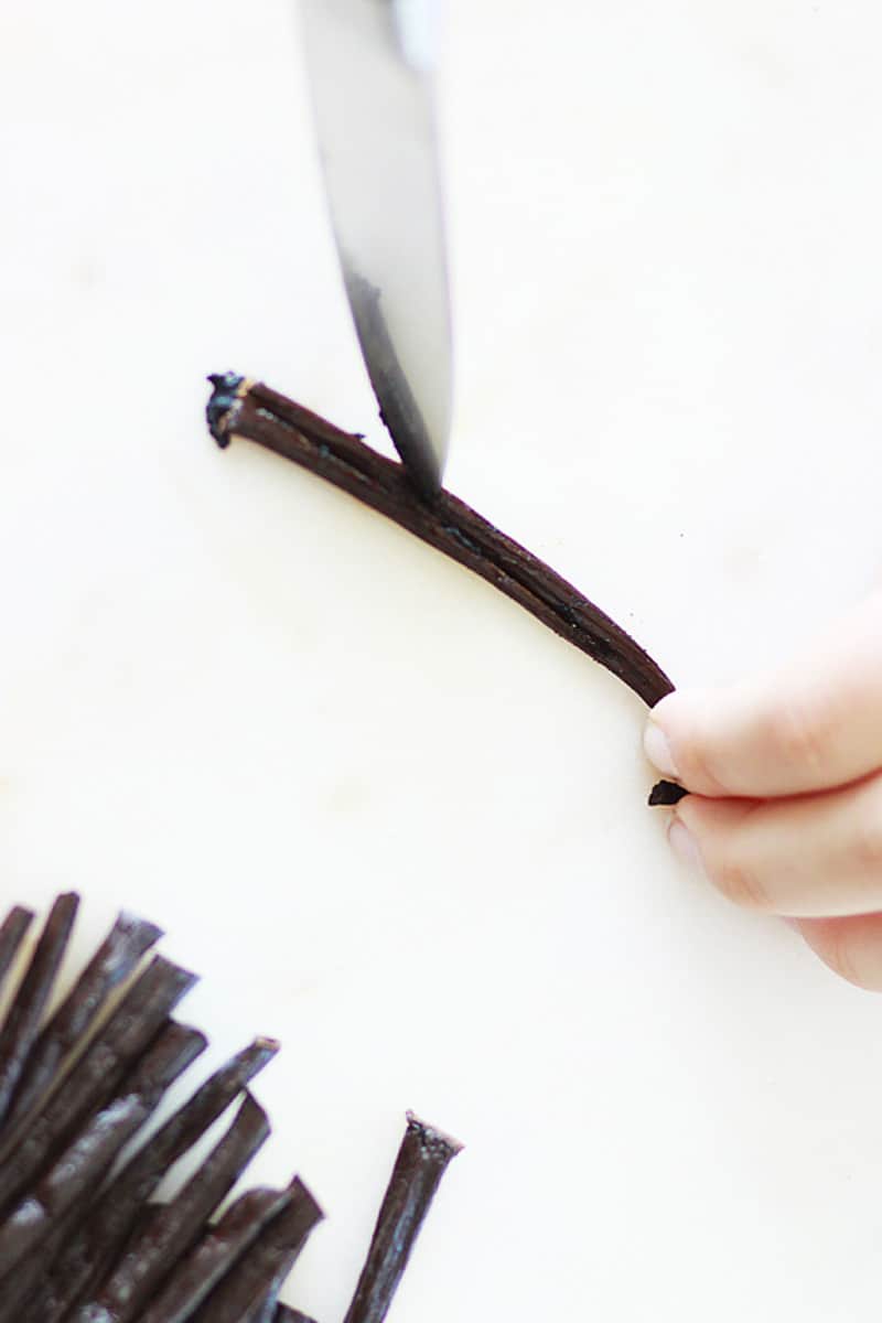 a knife slicing vanilla beans down the center