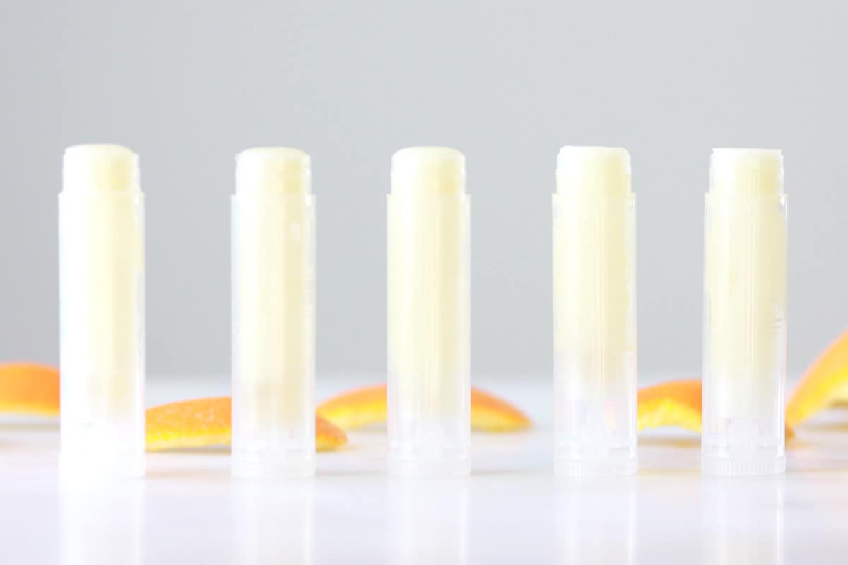 tubes of lip balm with orange peels in the background