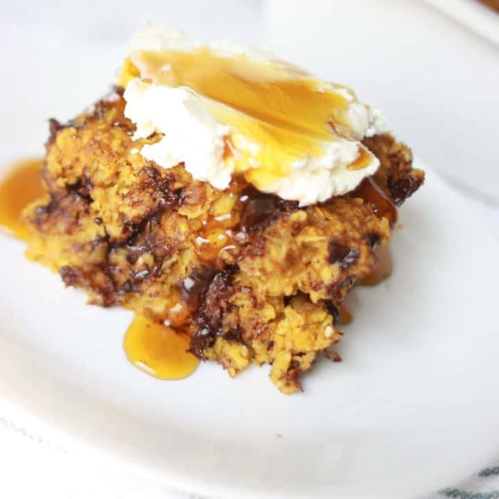 a plate with a serving on pumpkin baked oatmeal with chocolate chips in it and cream cheese and maple syrup on top