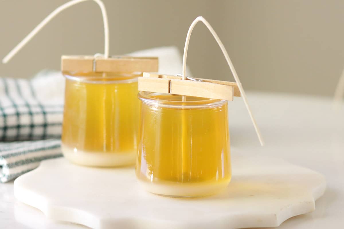 melted beeswax in two glass jars with wicks in the centers