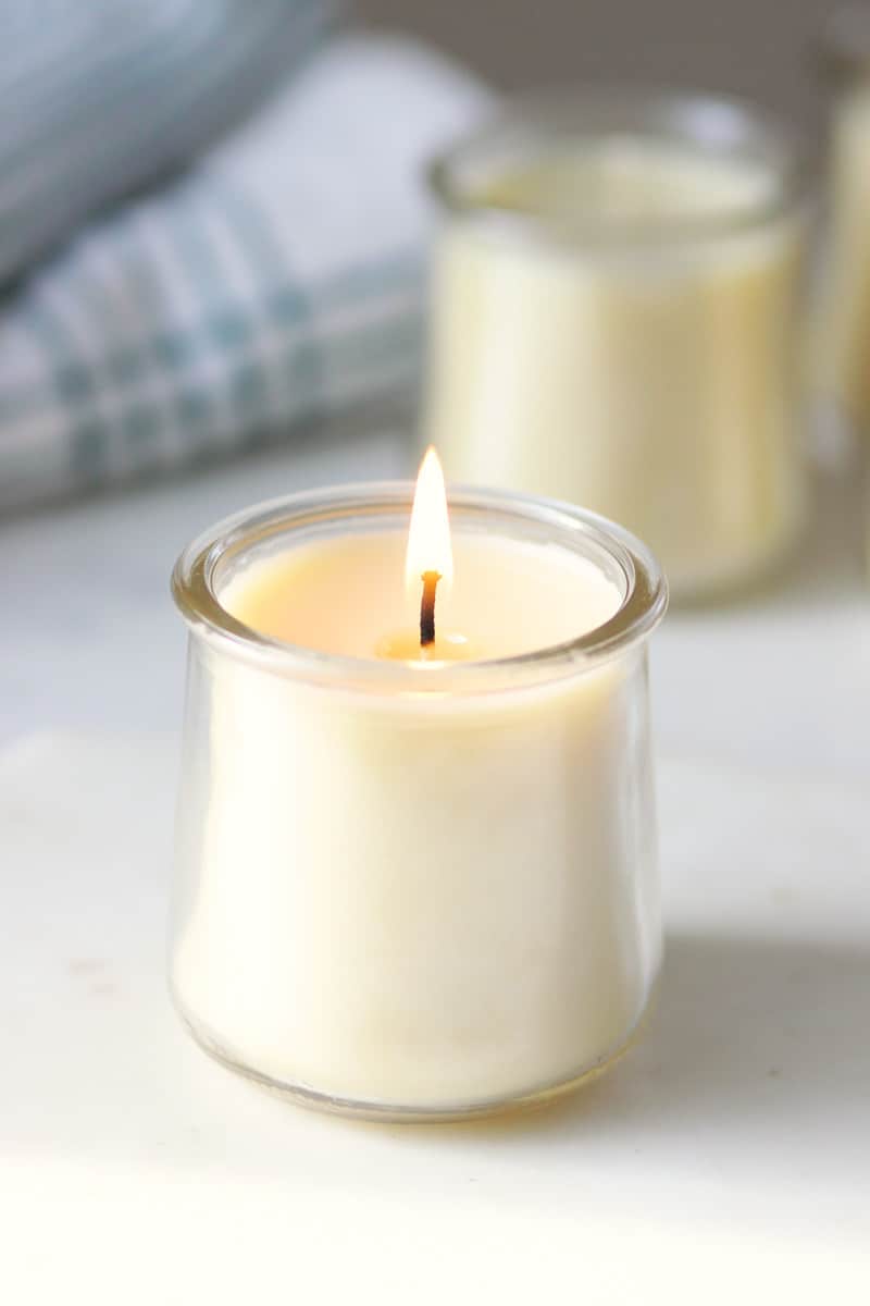 a lit beeswax candle in a oui yogurt jar