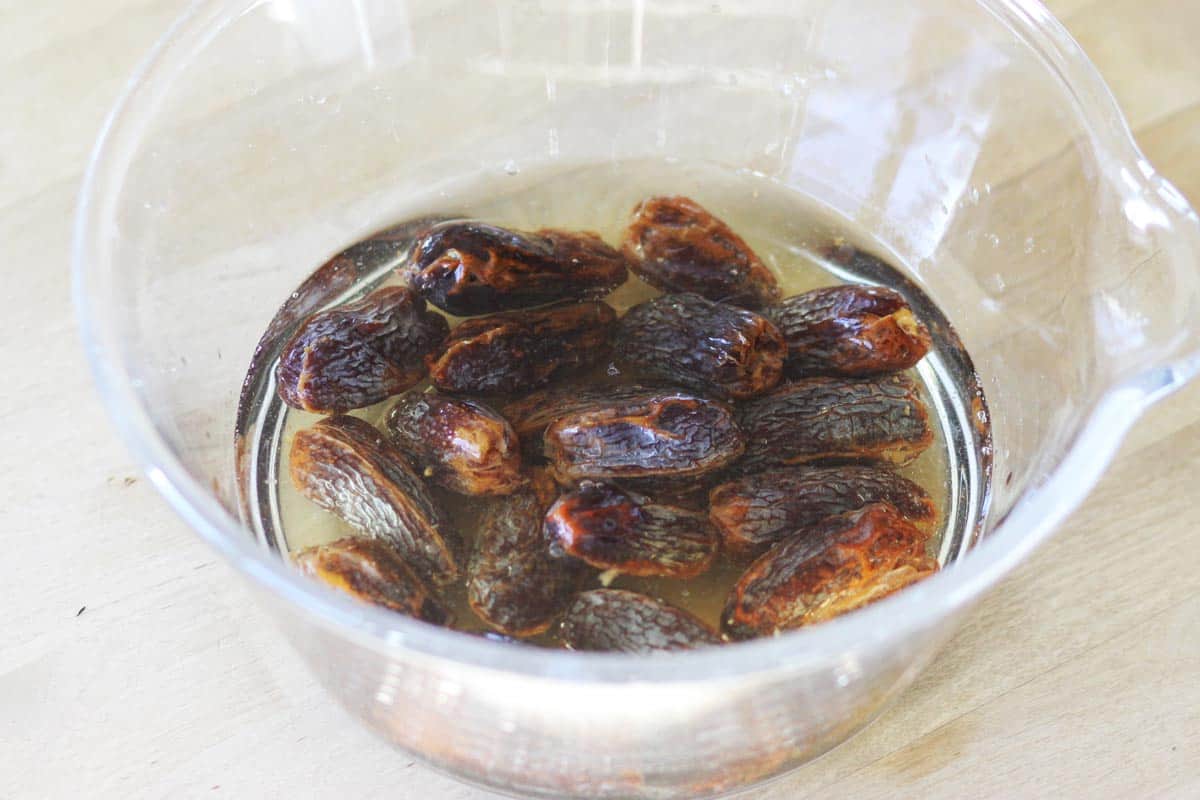 whole medjool dates are soaking in a bowl of water