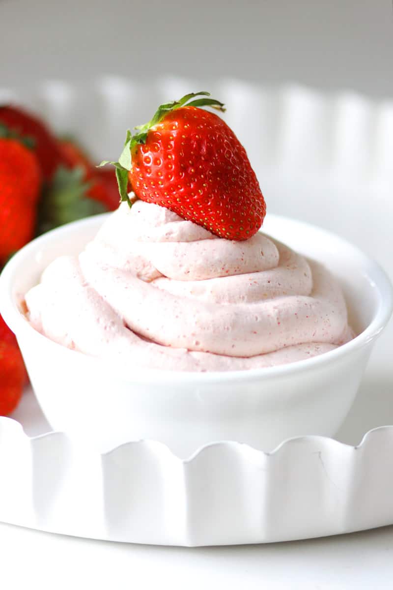 a white bowl with strawberry whipped cream in it and fresh strawberries set next to it