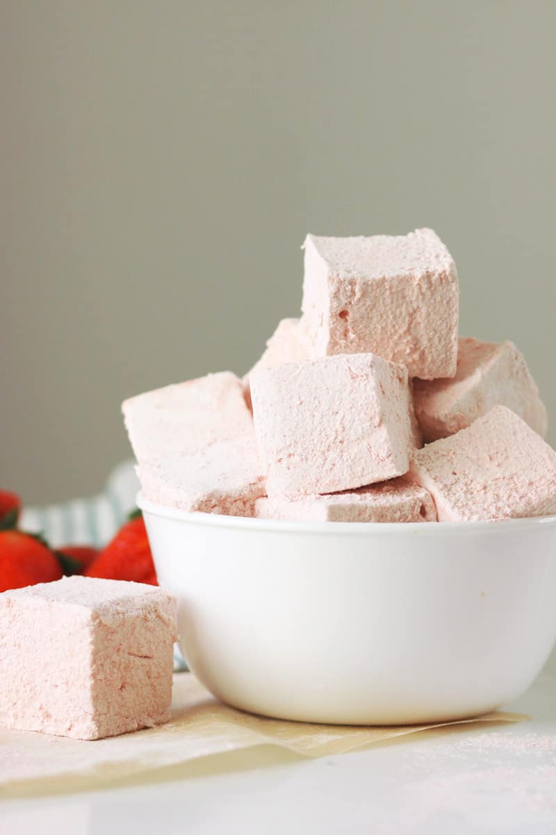 a bowl of homemade strawberry marshmallows with fresh strawberries