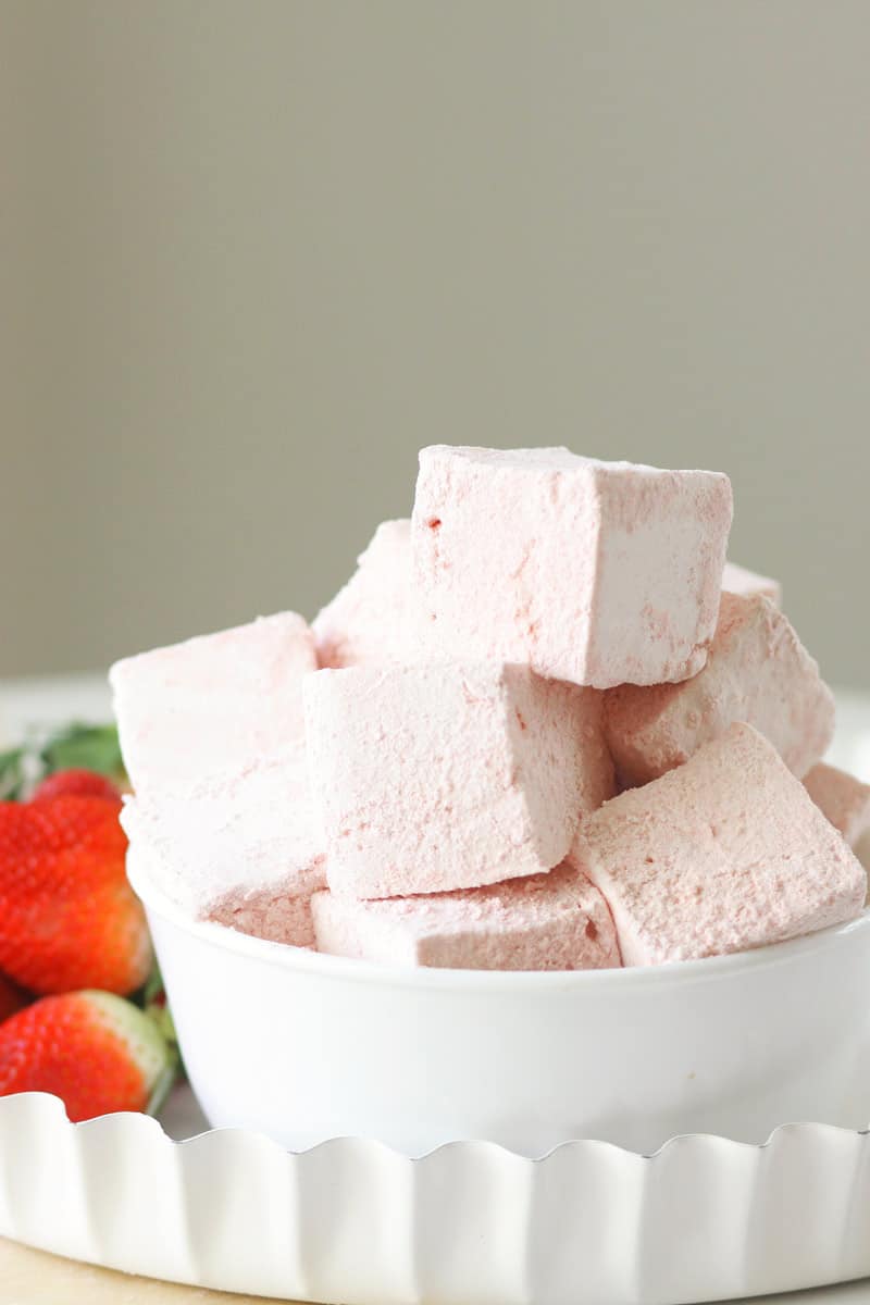 a bowl of homemade strawberry marshmallows with fresh strawberries