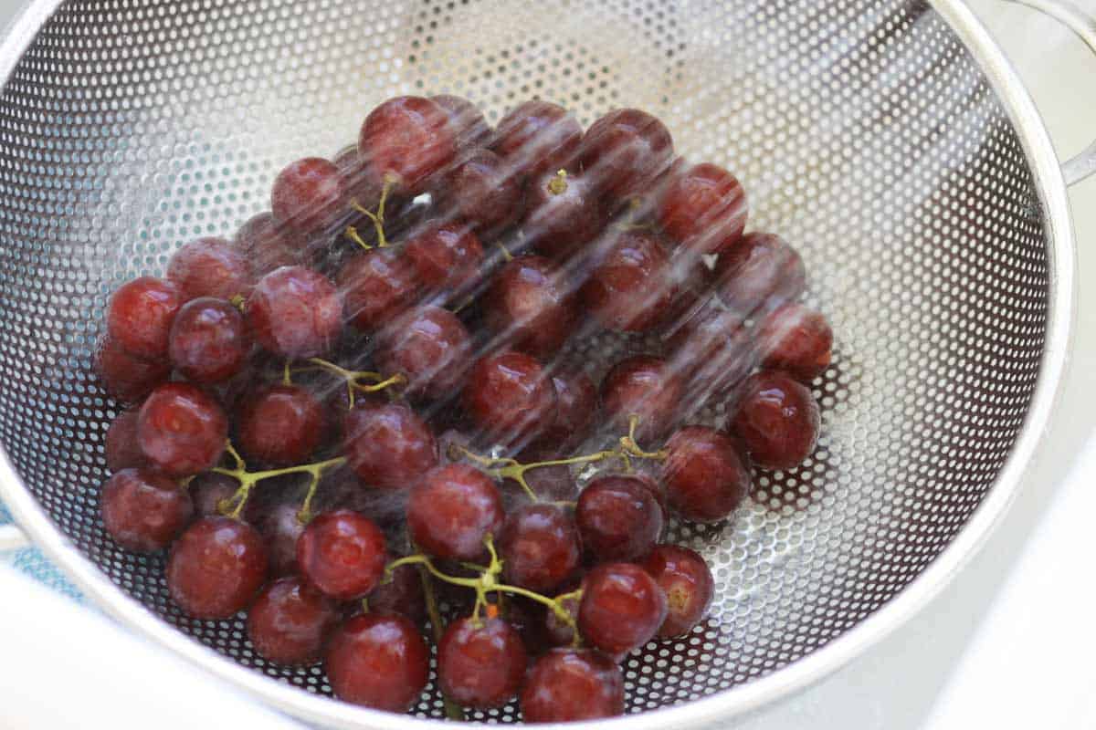 grapes being washed in a strainer