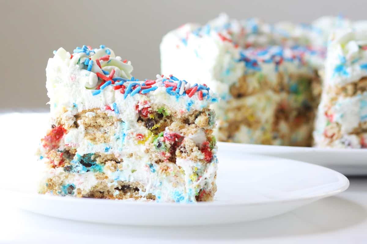 a slice of icebox cake layered with m&m cookies and topped with 4th of July sprinkles