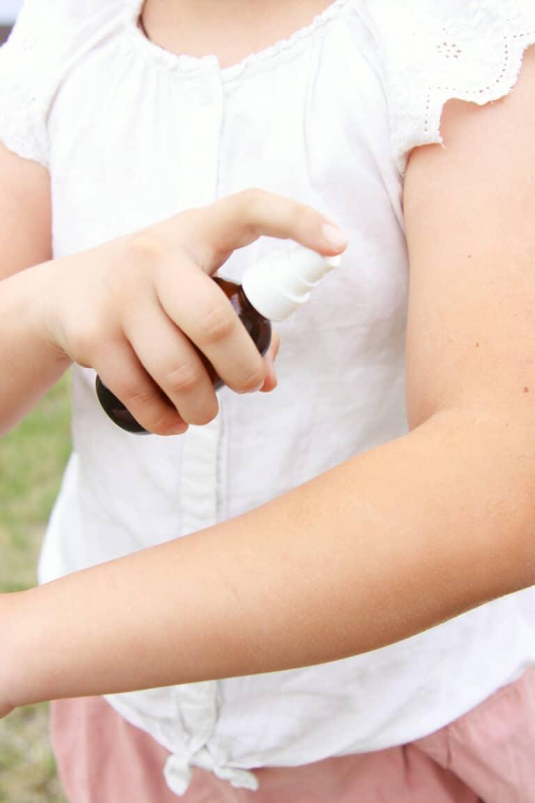 a girl spraying her arm with a small amber spray bottle