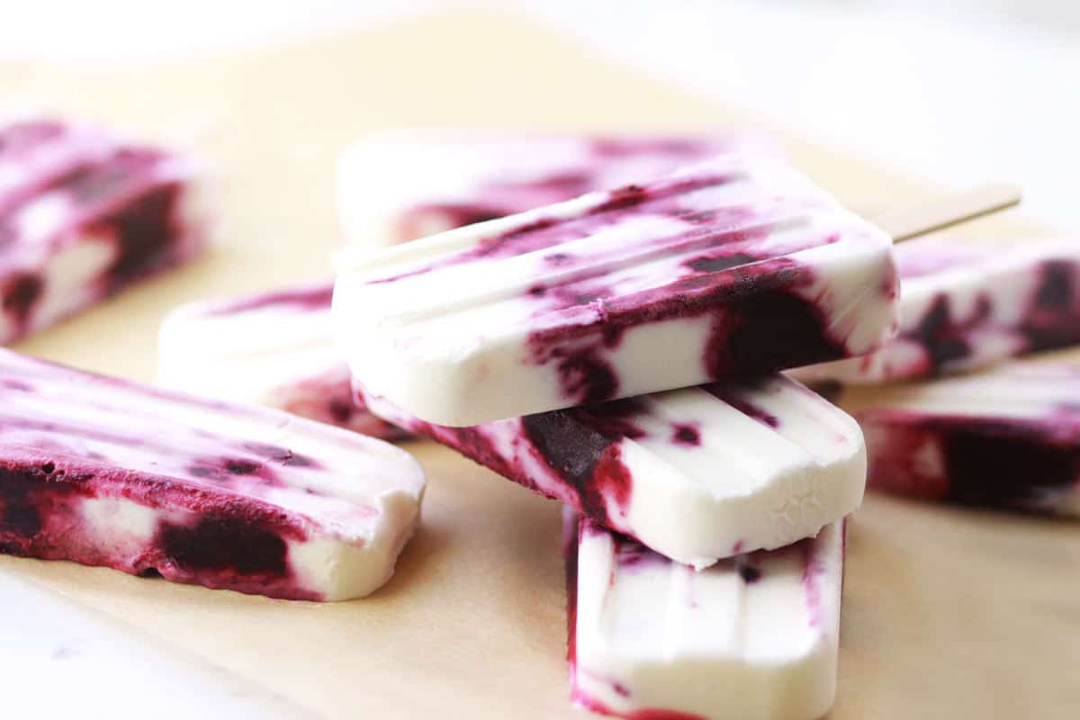 greek yogurt and mixed berry popsicles on a piece of parchment paper