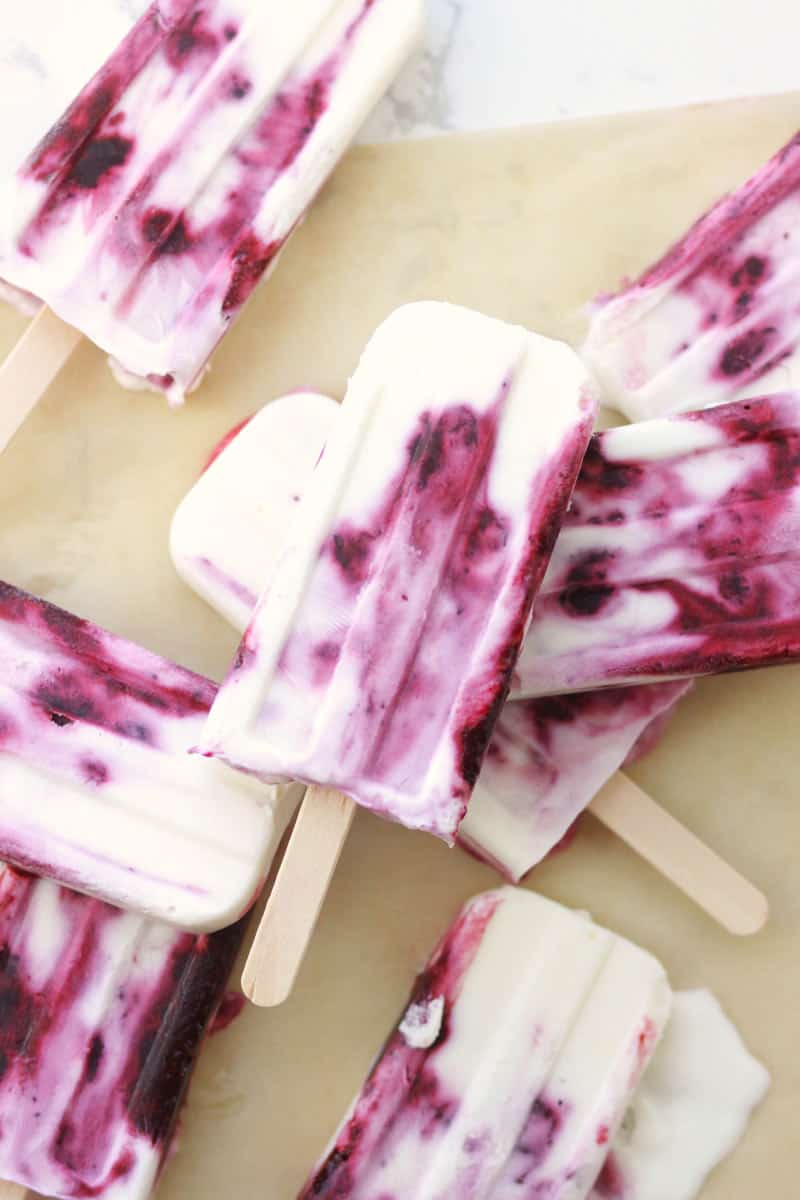 several yogurt and berry popsicles on parchment paper.