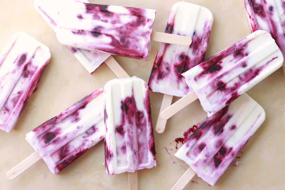 several yogurt and berry popsicles on parchment paper.