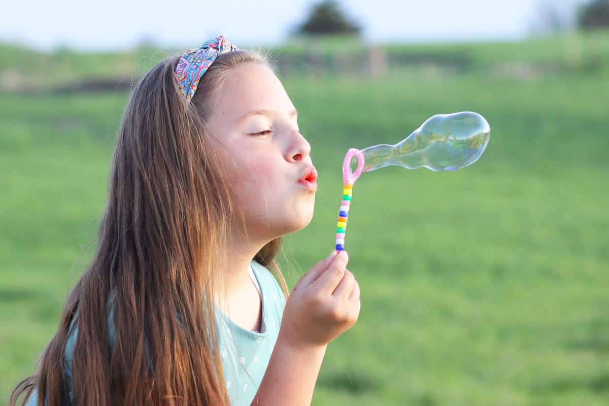 a girl blowing bubbles with a homemade bubble wand