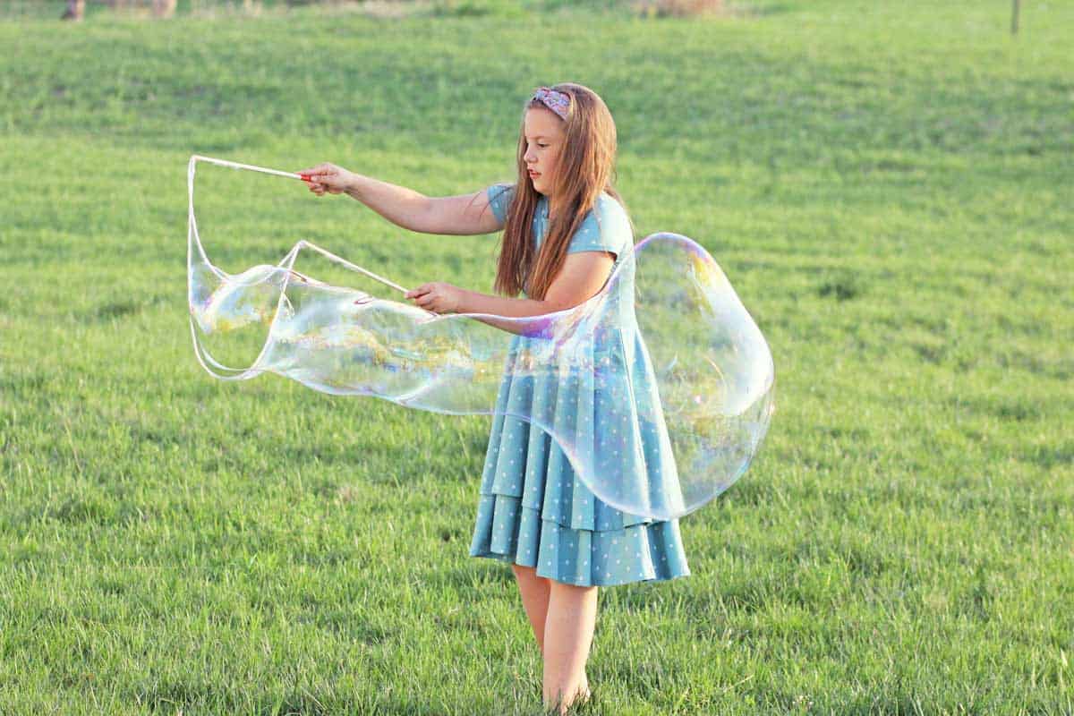 a girl making giant bubbles with a bubble wand