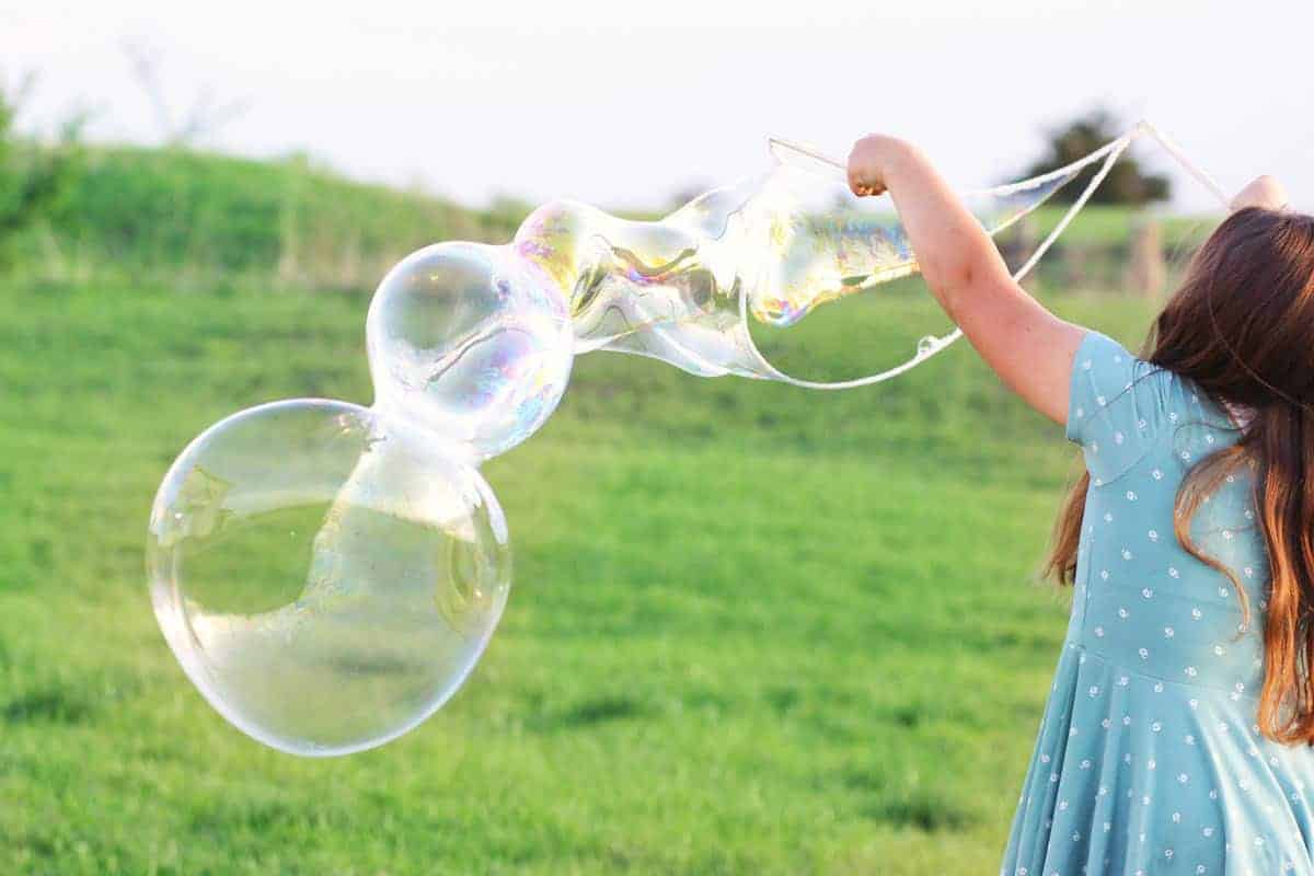 a girl making giant bubbles with a bubble wand