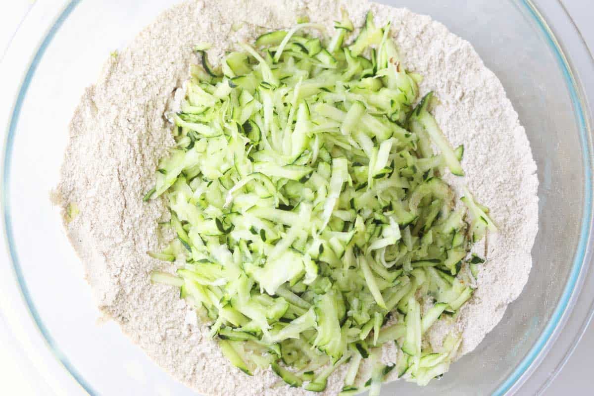 shredded zucchini in a bowl with whole wheat flour