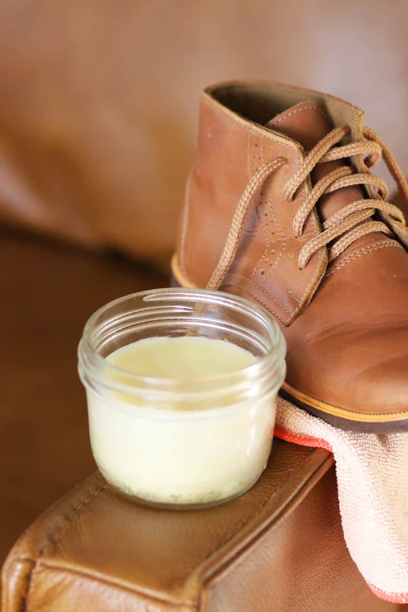 a jar of leather conditioner on a leather couch with a leather boot in the background