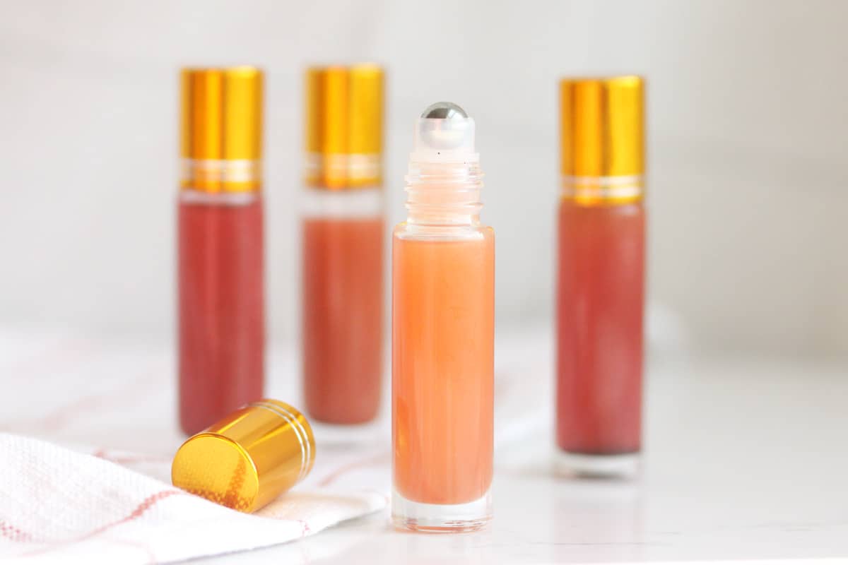 a pink lip gloss in a roller ball bottle with several bottles in the background