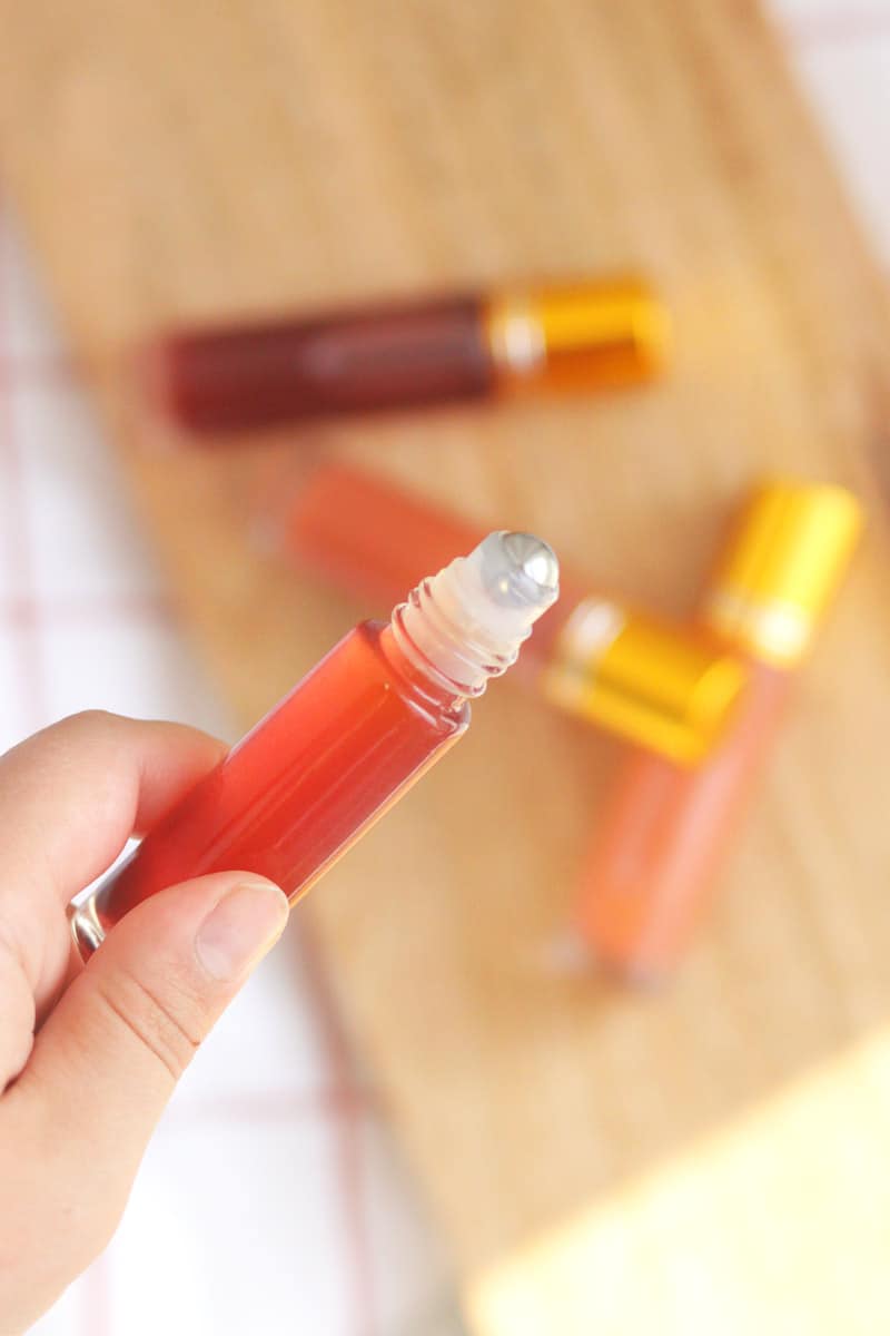 a pink lip gloss in a roller ball bottle with several bottles in the background