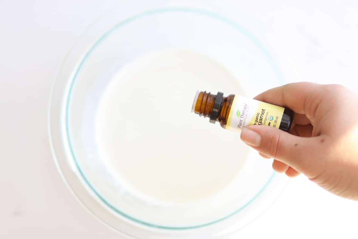 Bergamot essential oil being dripped into a bowl of liquid deodorant