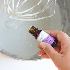 lavender essential oil being added to a kitchenaid mixer of homemade diaper rash cream