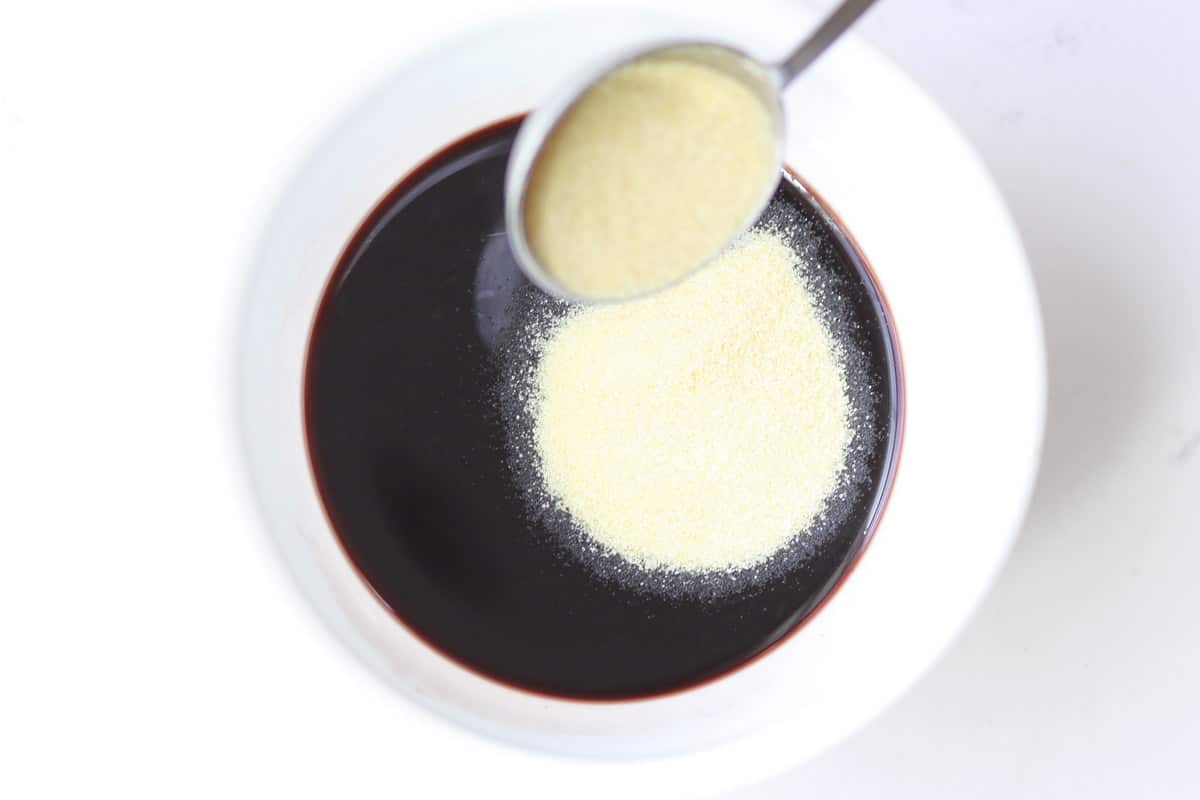 gelatin powder being added to elderberry syrup