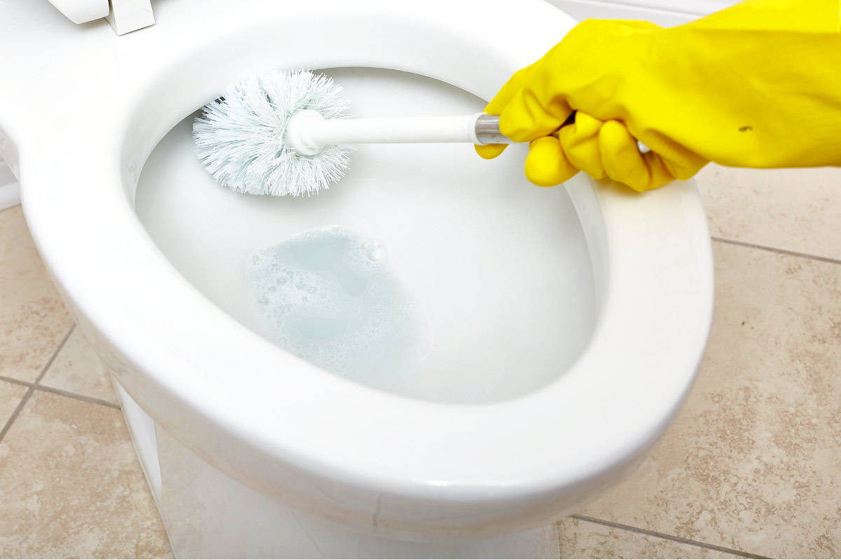 a hand in a rubber glove scrubbing a toilet bowl with a toilet brush