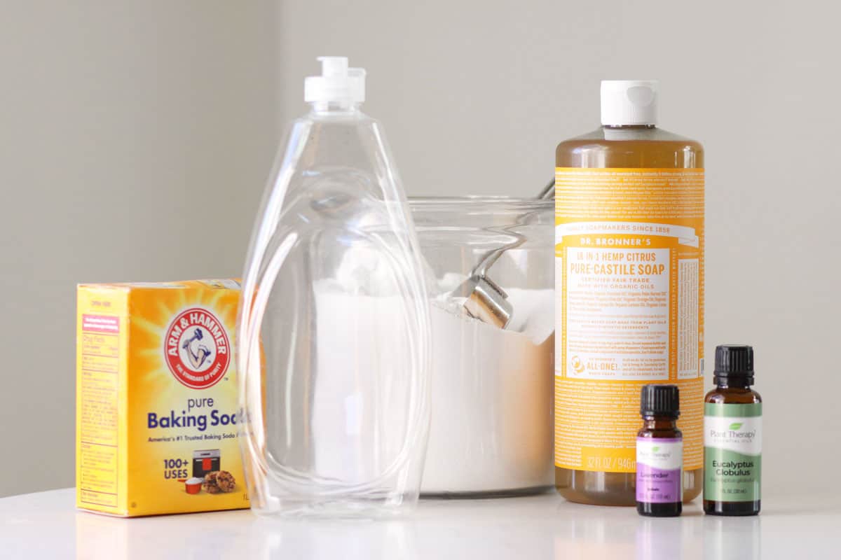 baking soda, castile soap, borax, essential oils and an empty dish soap squeeze bottle on  counter