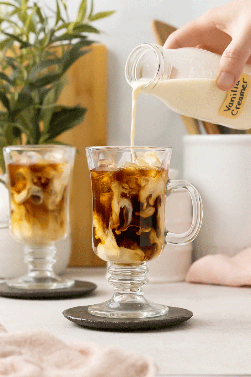 Homemade coffee creamer being poured into iced coffee.